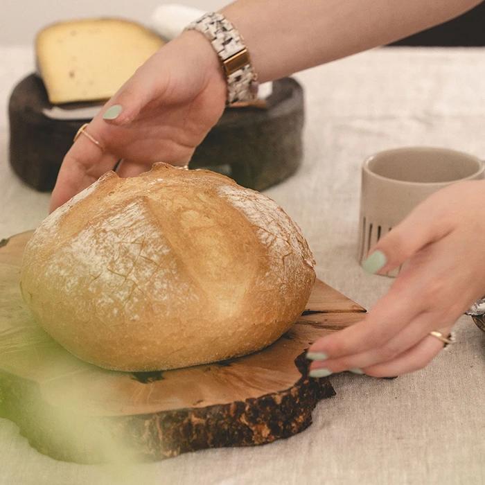 Freshly baked homemade bread served on a wooden platter with artisan cheeses nearby.