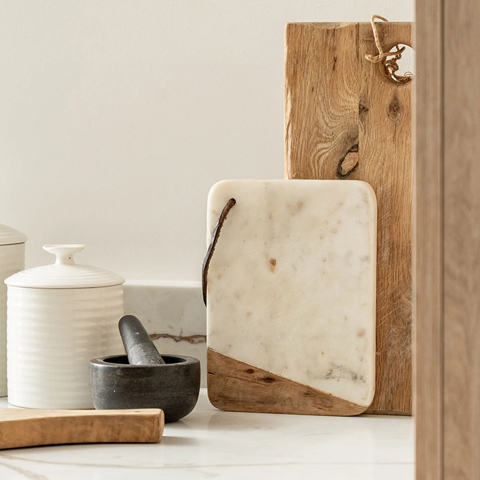 Beautiful kitchen with marble and wooden cutting boards serving bowls and mortar.