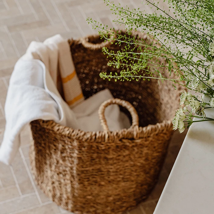 Woven basket with natural blankets and lush greenery on a rustic dining table.