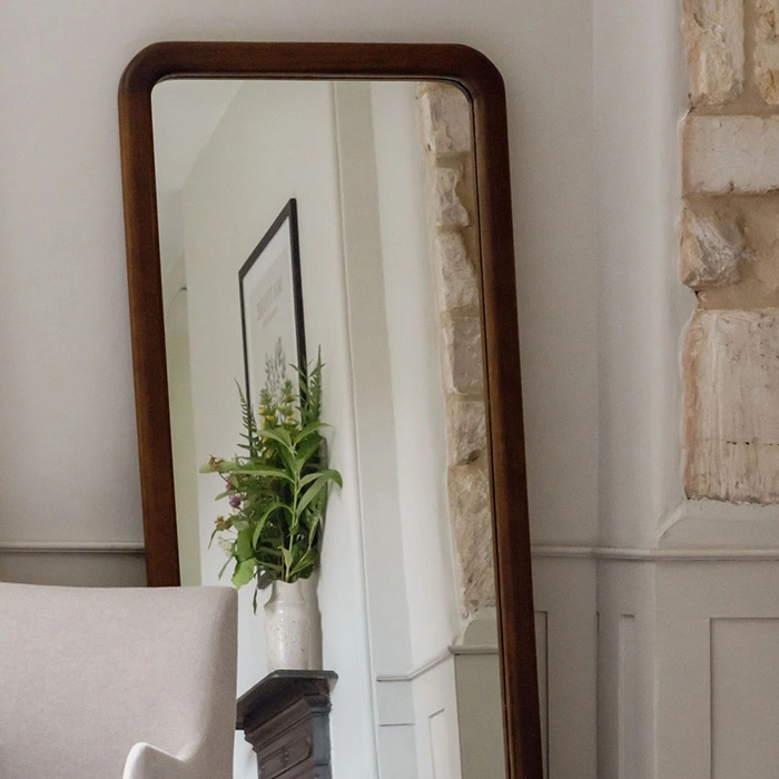Elegant home decor featuring a wooden framed mirror with botanical greenery accents.