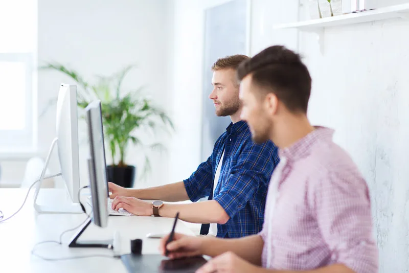 Two men in front of computer monitors.