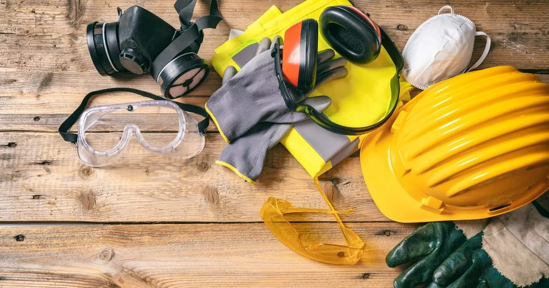 Work safety. Construction site protective equipment on wooden background, flat lay.