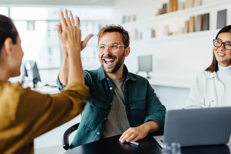 Successful business people (man and a woman) giving each other a high five in a meeting.