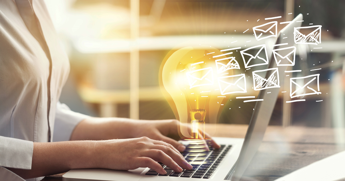 A person typing on a laptop with a glowing light bulb and email icons around it.