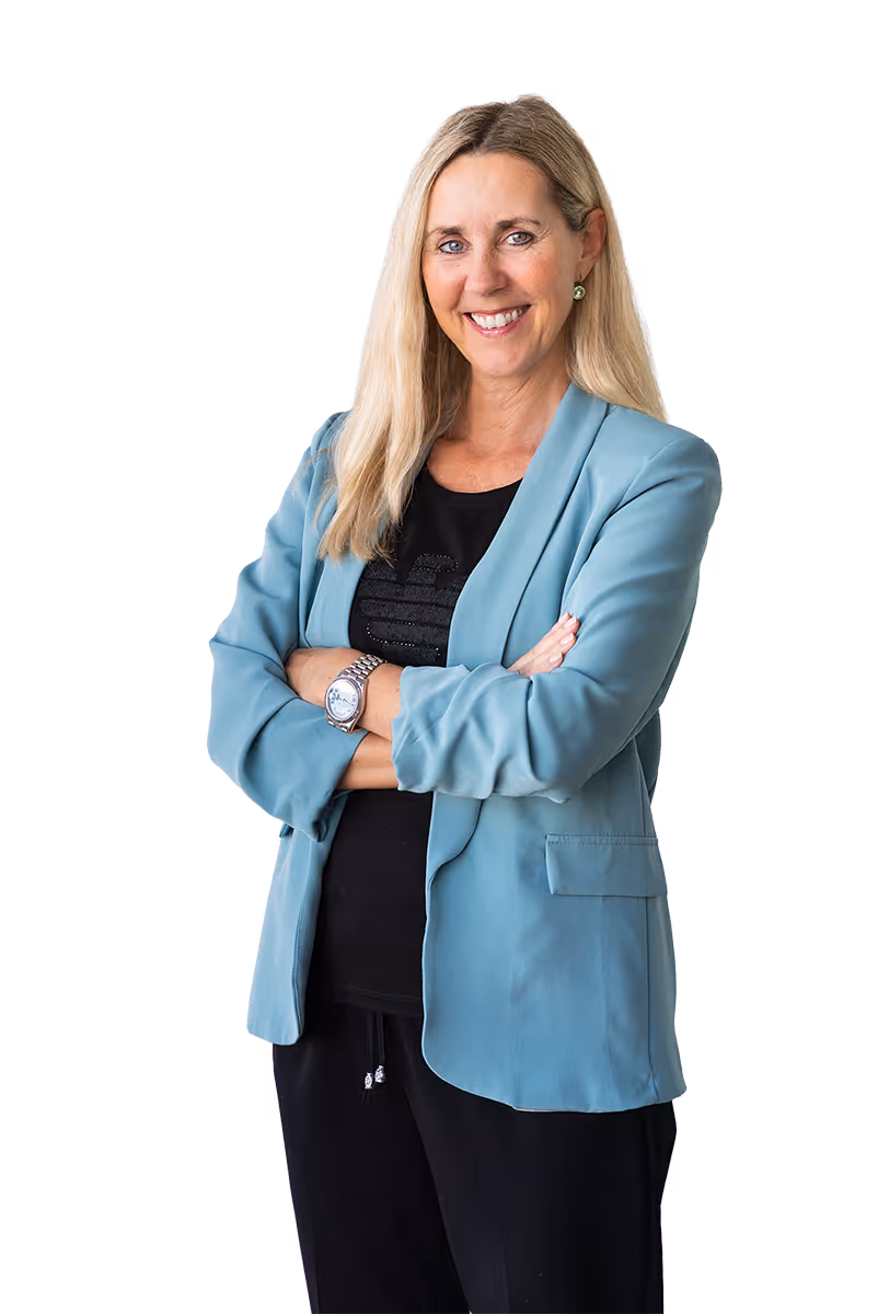 Smiling woman with long blonde hair wearing a light blue blazer over a black shirt with arms crossed.