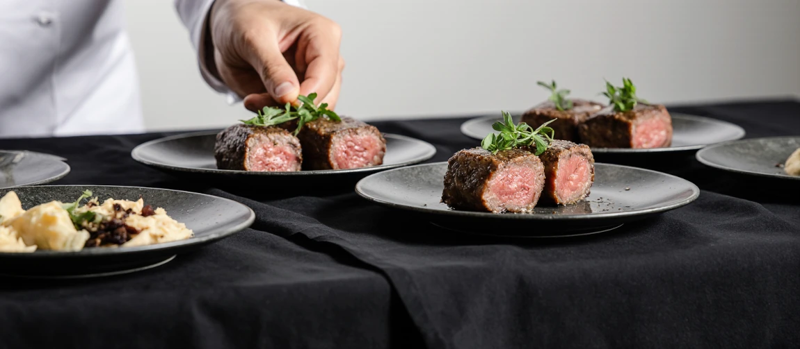 A chef presenting a fine dining Filet Mignon.