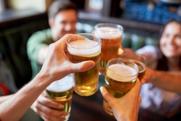 Menschen stoßen mit Gläsern Bier in einer geselligen Runde an.