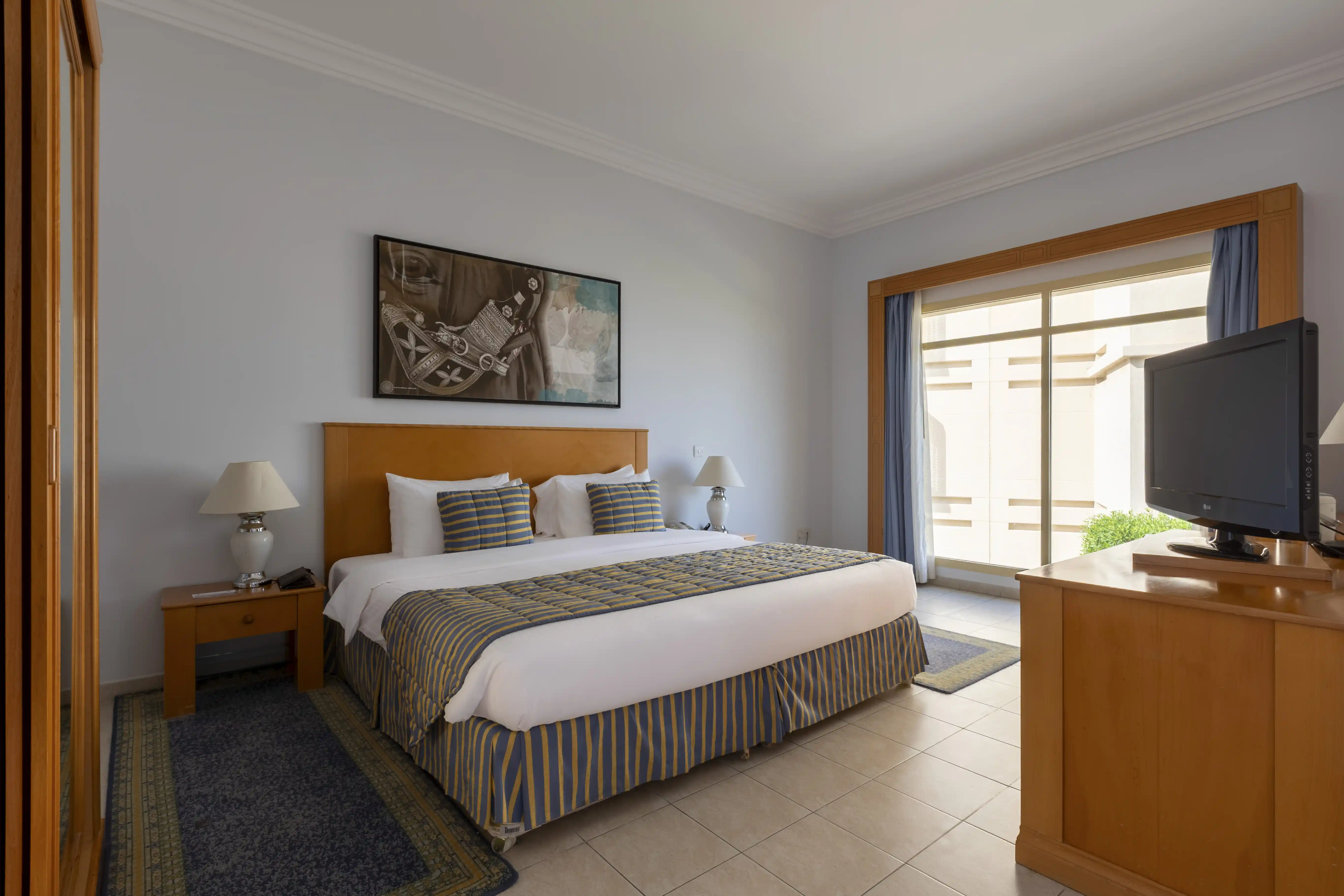 A wide view of the King Chalet bedroom, showing the neatly made bed, a large wardrobe, and a TV on a wooden dresser.