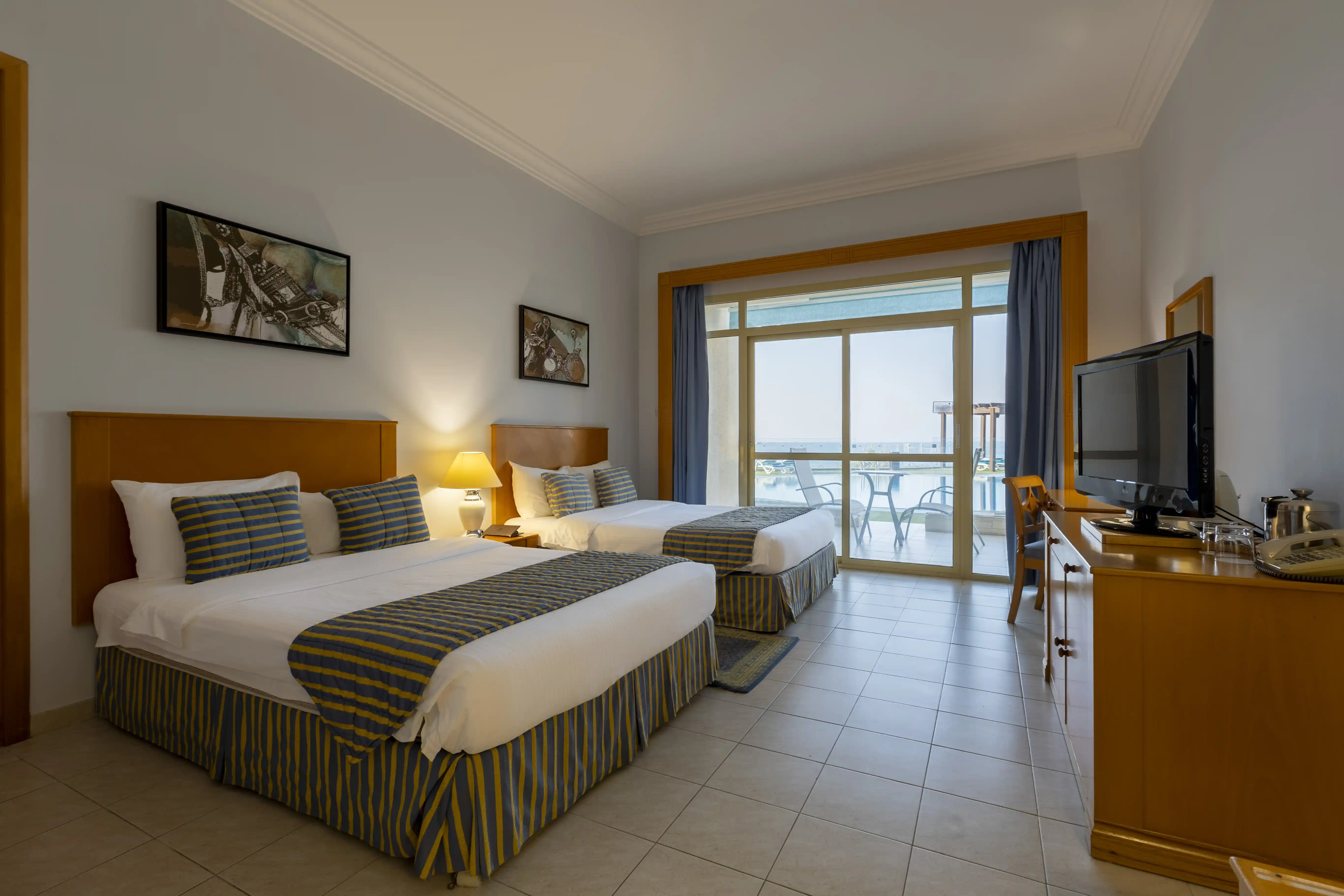 The spacious Panoramic Twin room, featuring two comfortable beds, a desk, and a furnished balcony with a sea view.