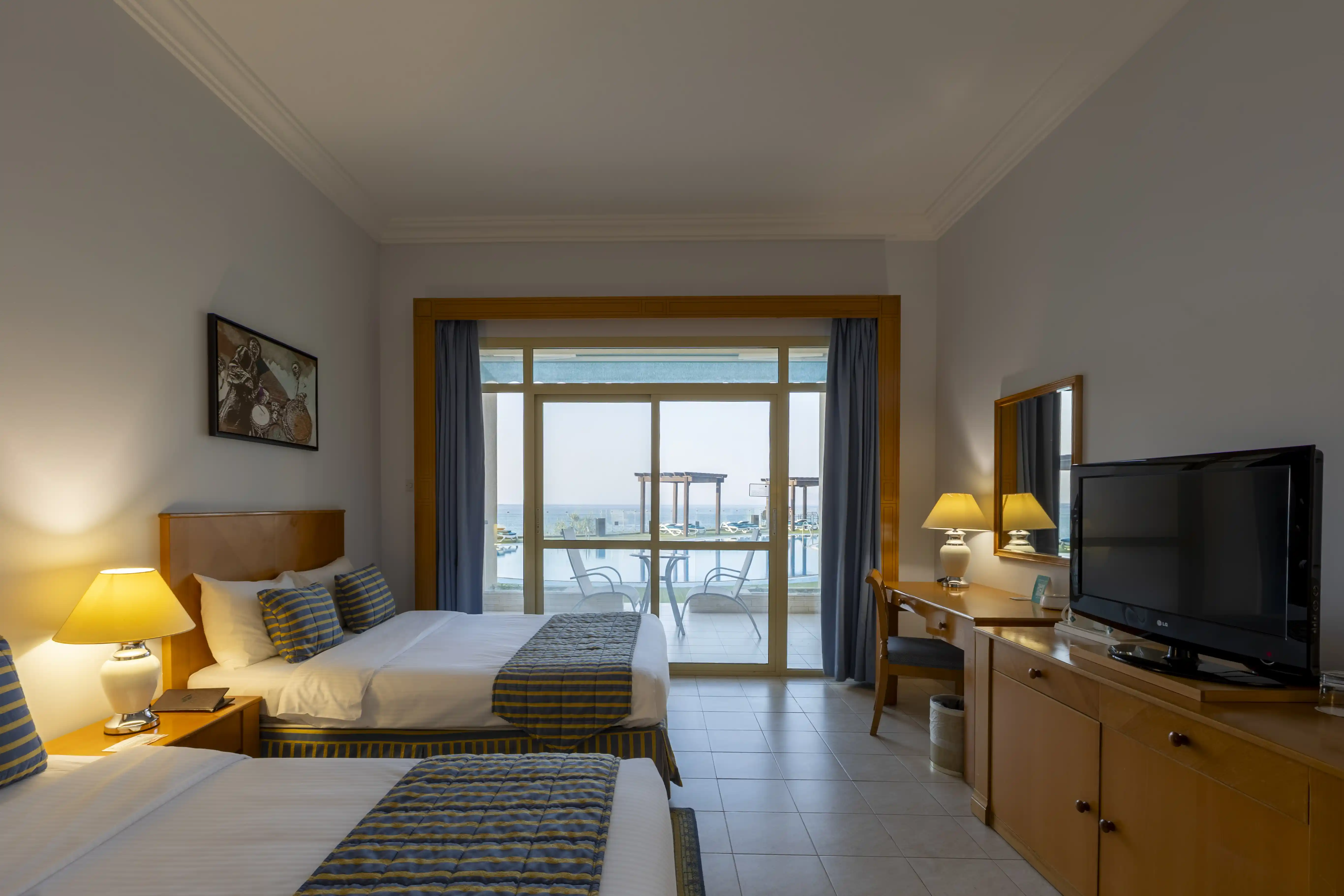 A view of the Panoramic Twin room at Atana Khasab, showing the two beds and the large window overlooking the pool and sea.