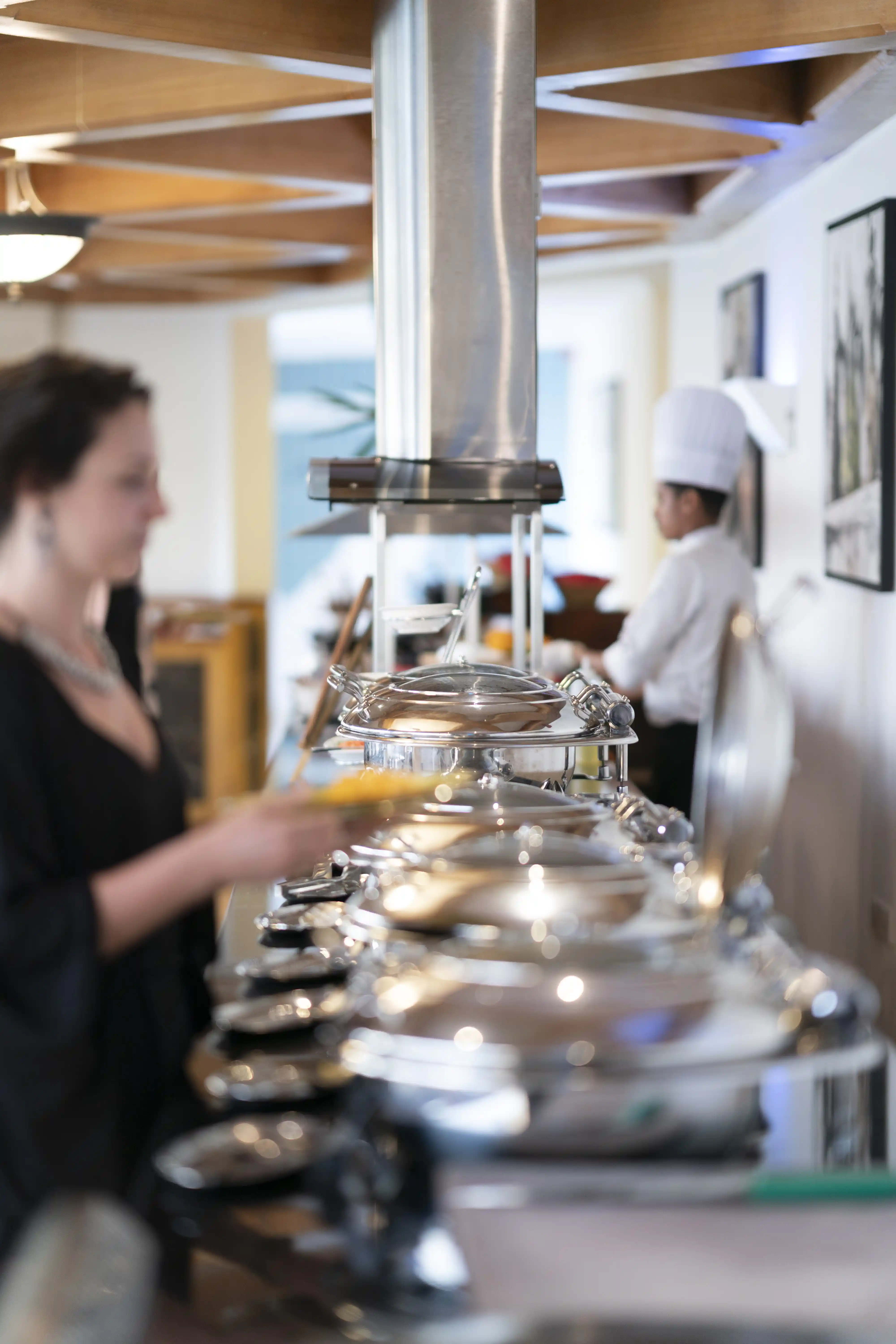 A guest selects a meal from the hot buffet line, which features a variety of dishes in silver chafing dishes.