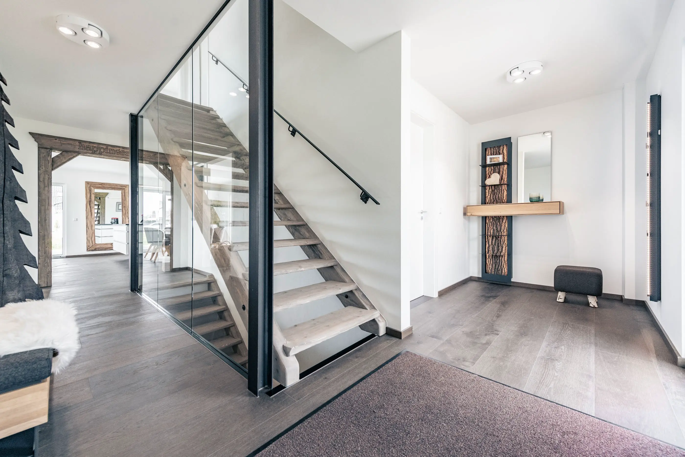 Treppe aus Holz mit Metallgerüst und Glasscheibe im Einfamilienhaus vom Jubiläumshaus  in Vöhringen, gebaut von Hauser Massivbau  