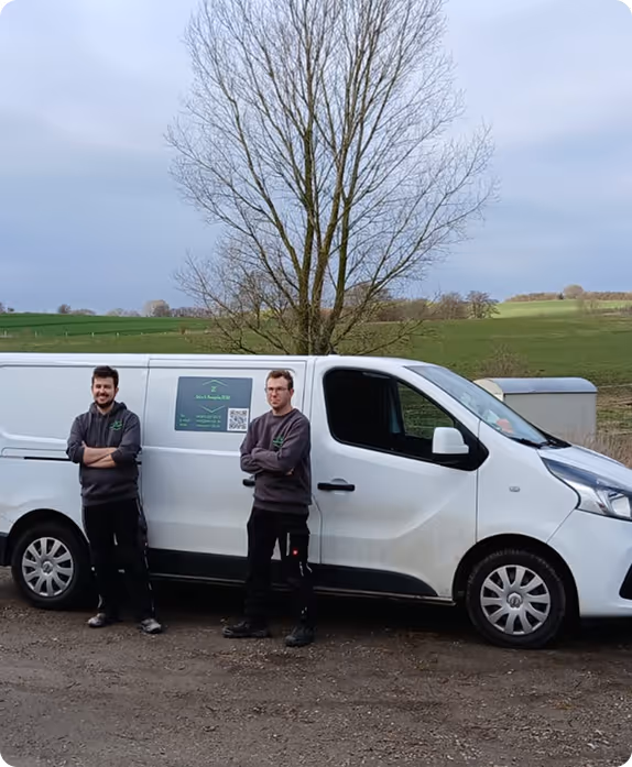 Zwei Männer stehen vor einem weißen Transporter mit grünem Firmenlogo auf dem Land.