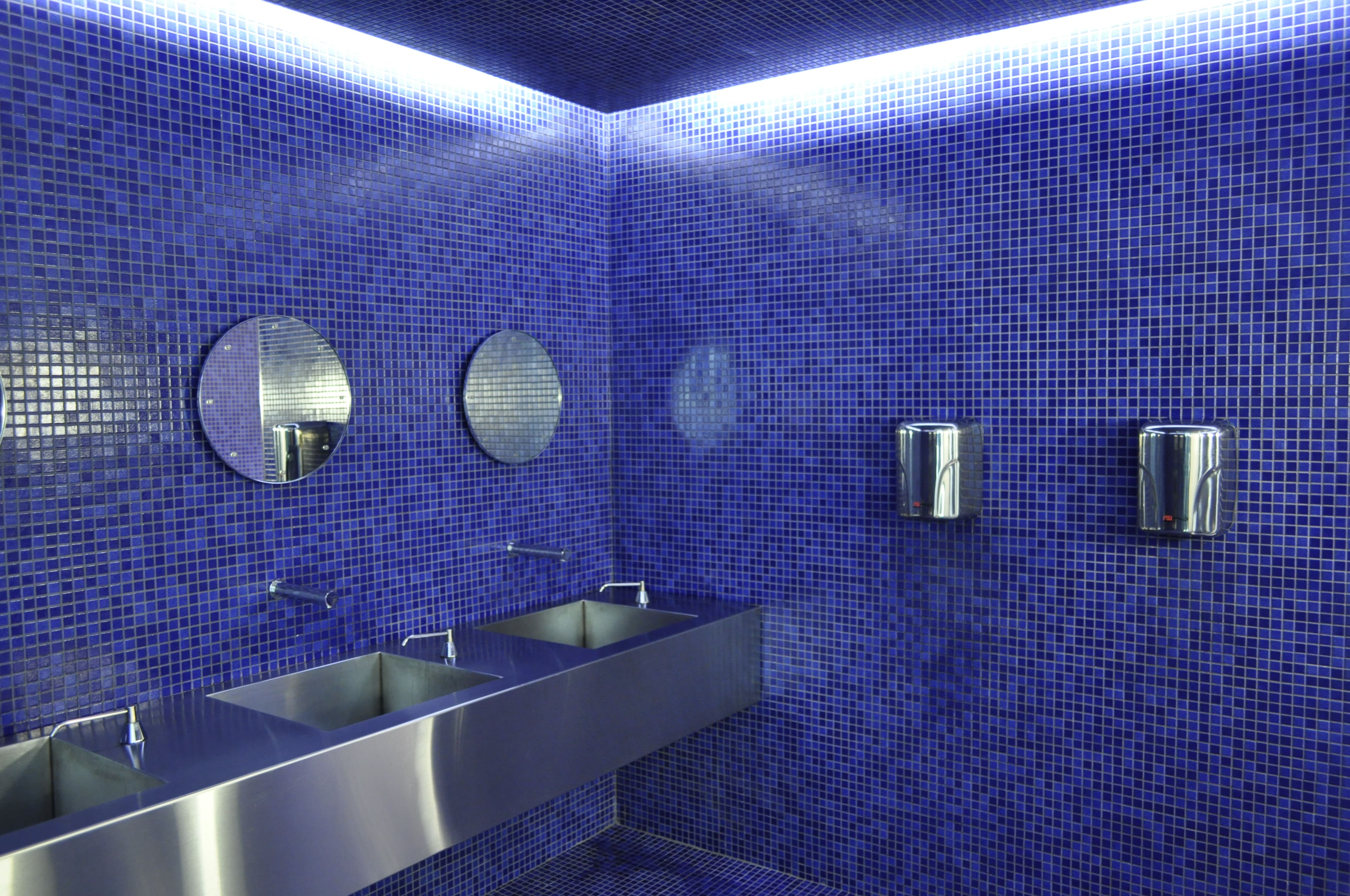 Modern commercial bathroom with tiled walls and stalls