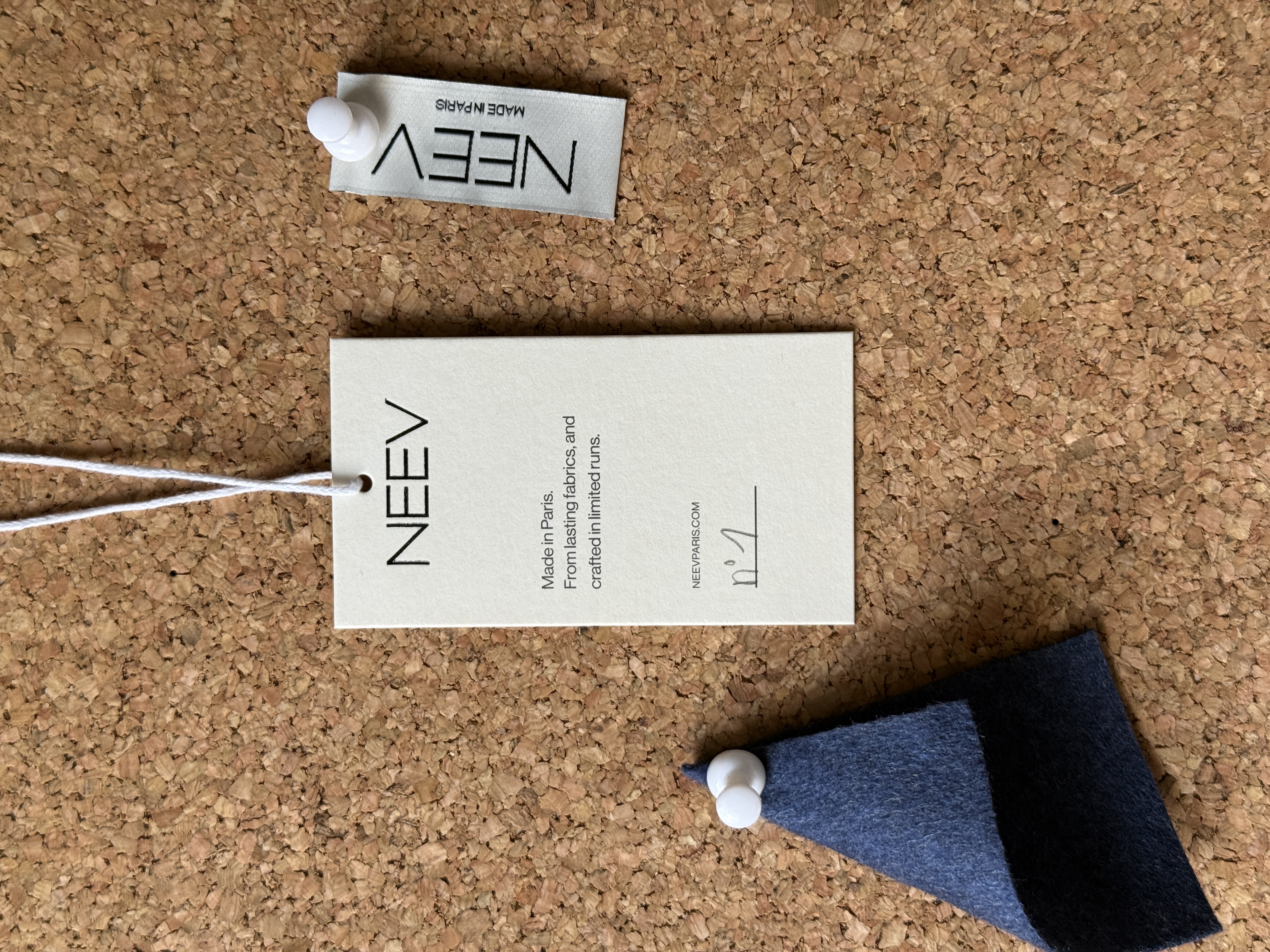 NEEV garment label in recycled paper and fabric swatch used in the development of permanent womenswear