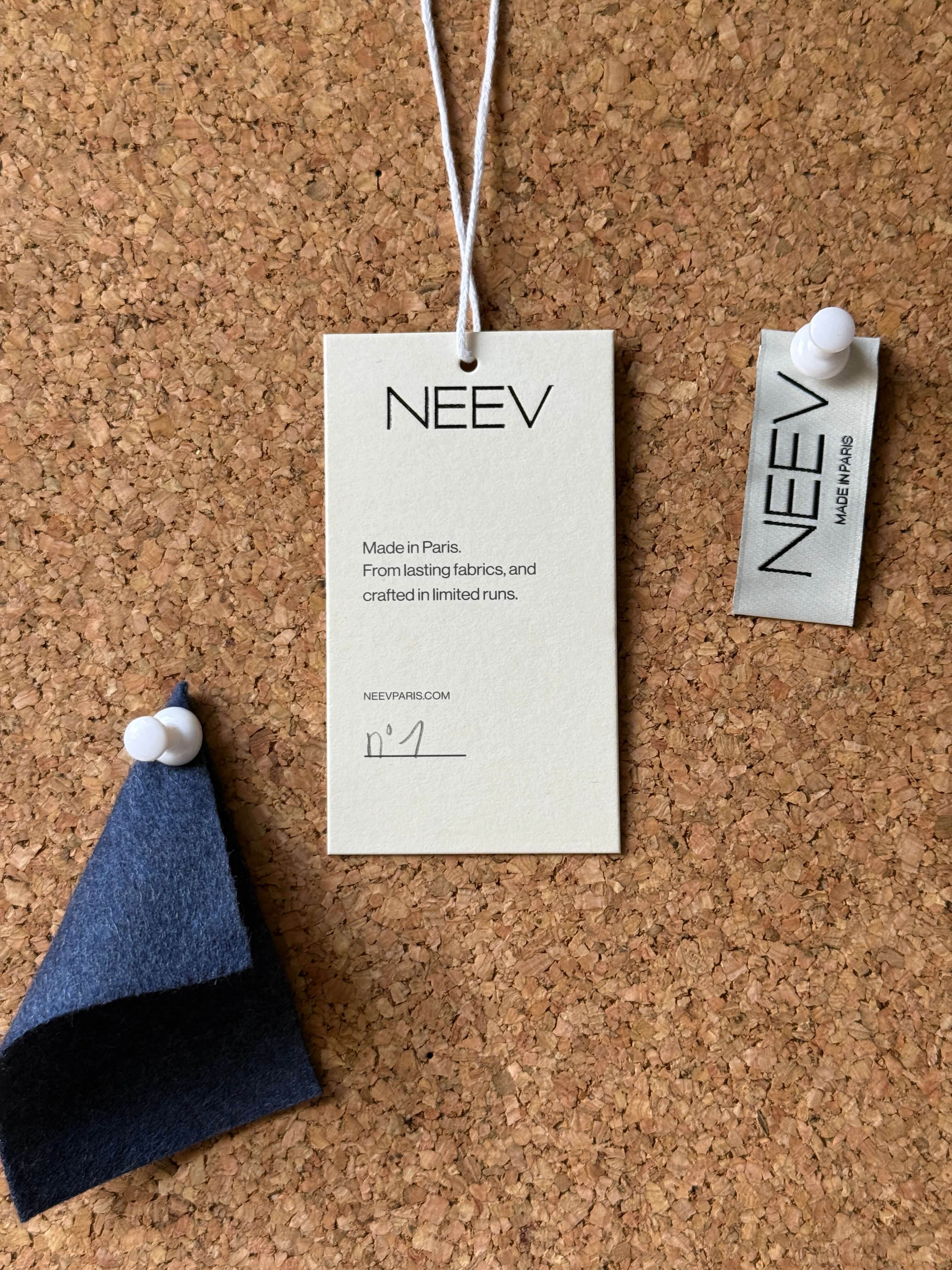 NEEV garment label in recycled paper and fabric swatch used in the development of permanent womenswear