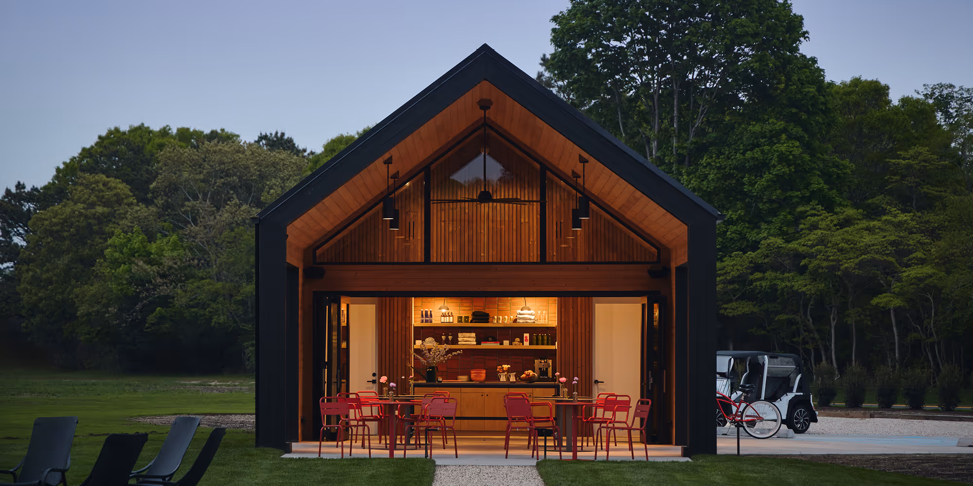 The Barn in the evening with the interior lit up and outdoor seating
