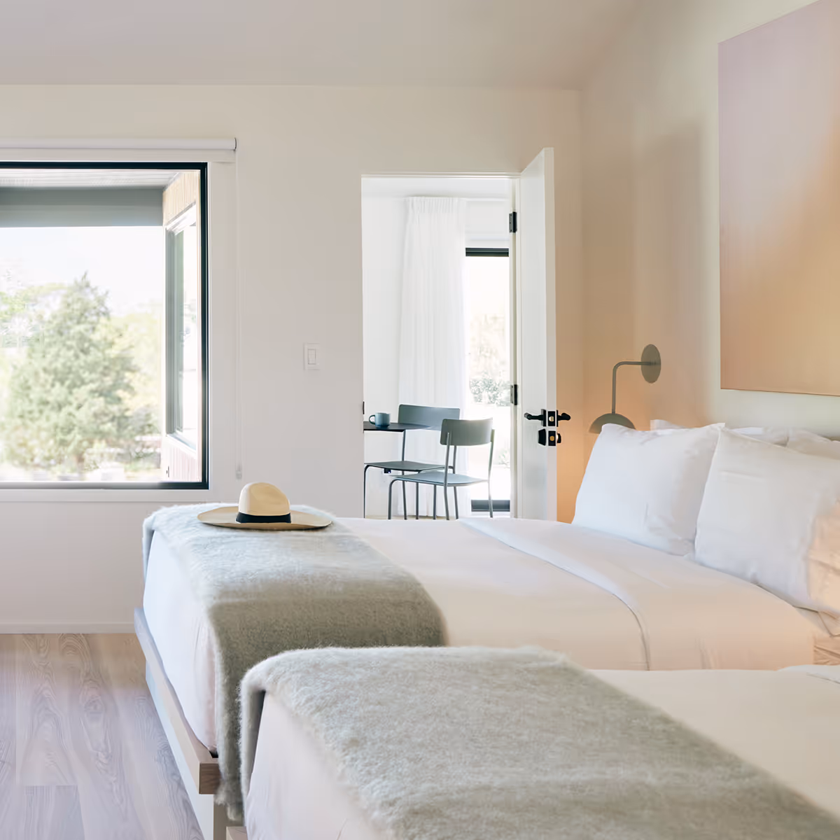 Side view of two queen beds looking towards a wall with a door leading to a private patio