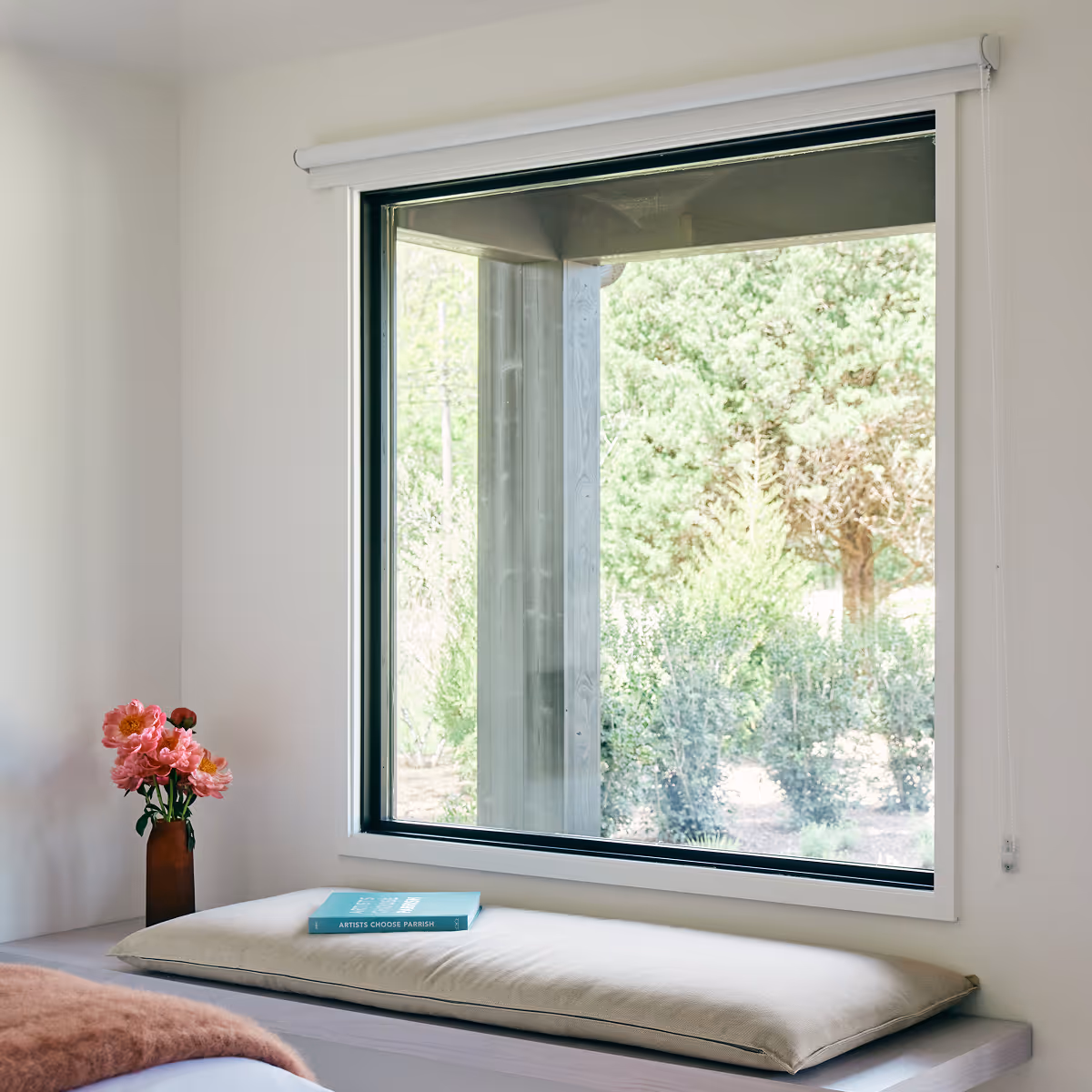 Edge of king bed with bench against wall with a large window