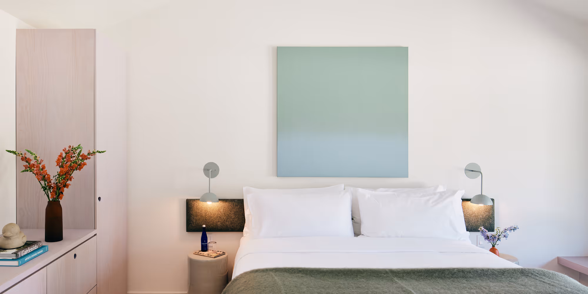 King bed with side table and sconce on the left and painting above the bed