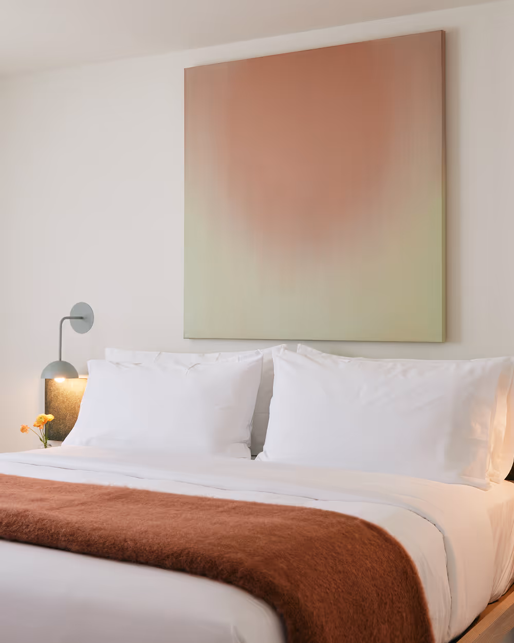 Angled view of king bed with painting above the bed