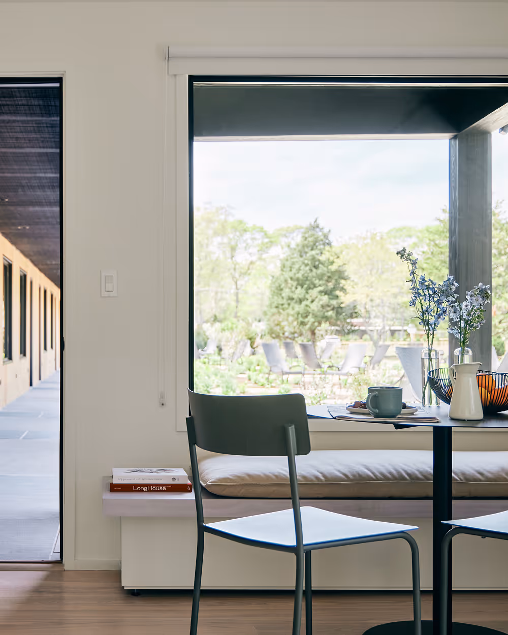 Dining set with table, two chairs, and bench against a large window wall and door left ajar