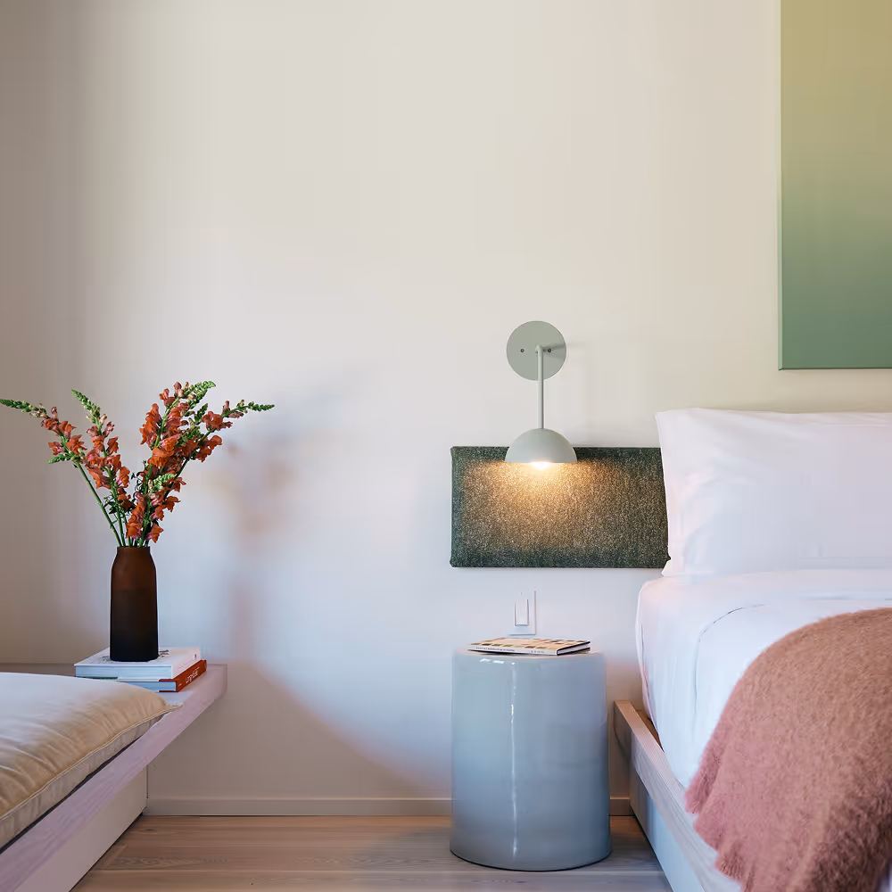 Close up view of king bed featuring a bouquet, side table, sconces, and the bed