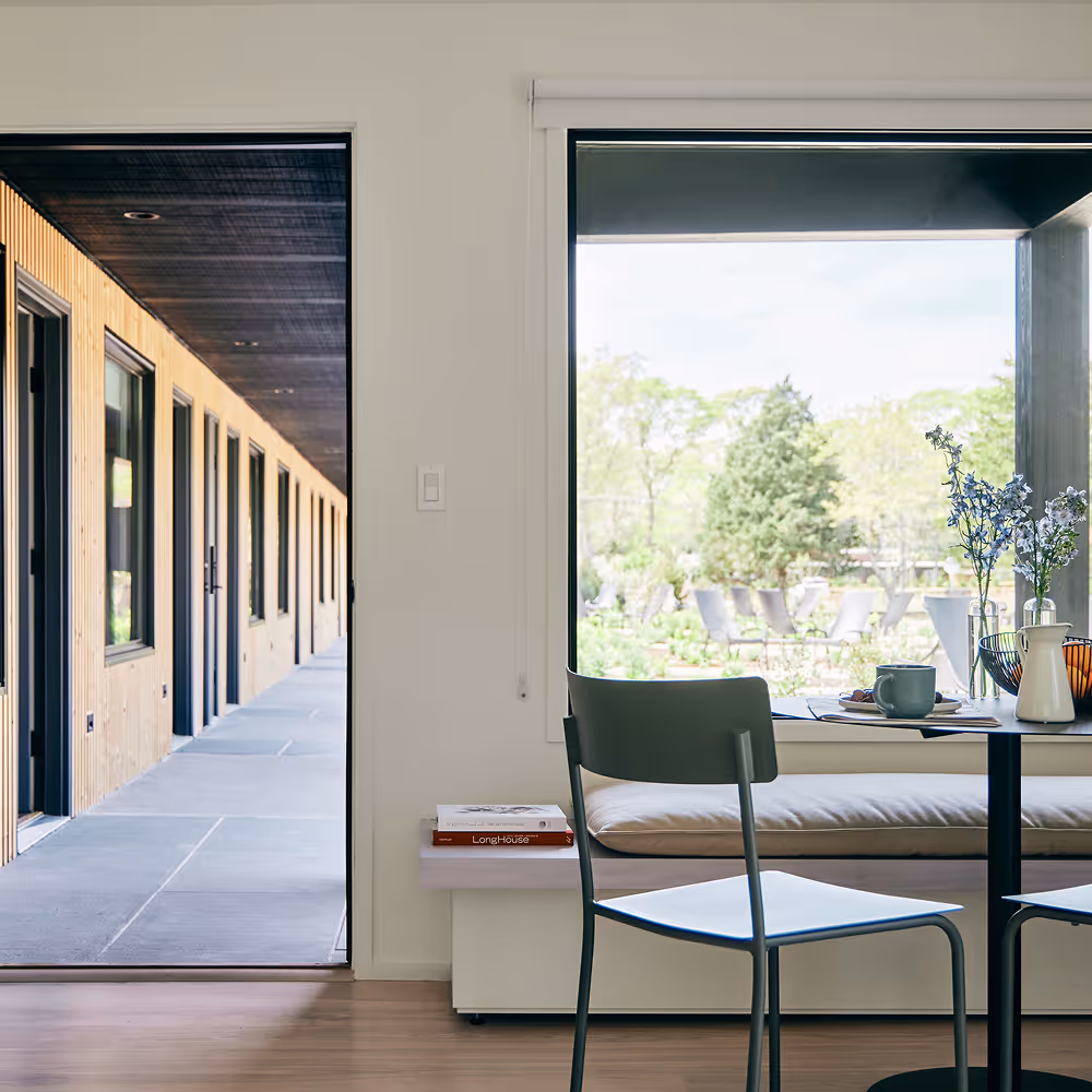 Dining set with table, two chairs, and bench against a large window wall and door left ajar