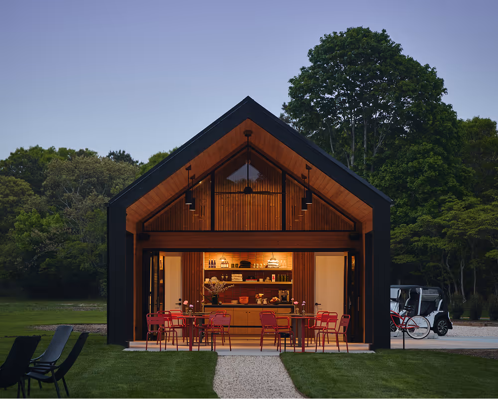 The Barn in the evening with the interior lit up and outdoor seating