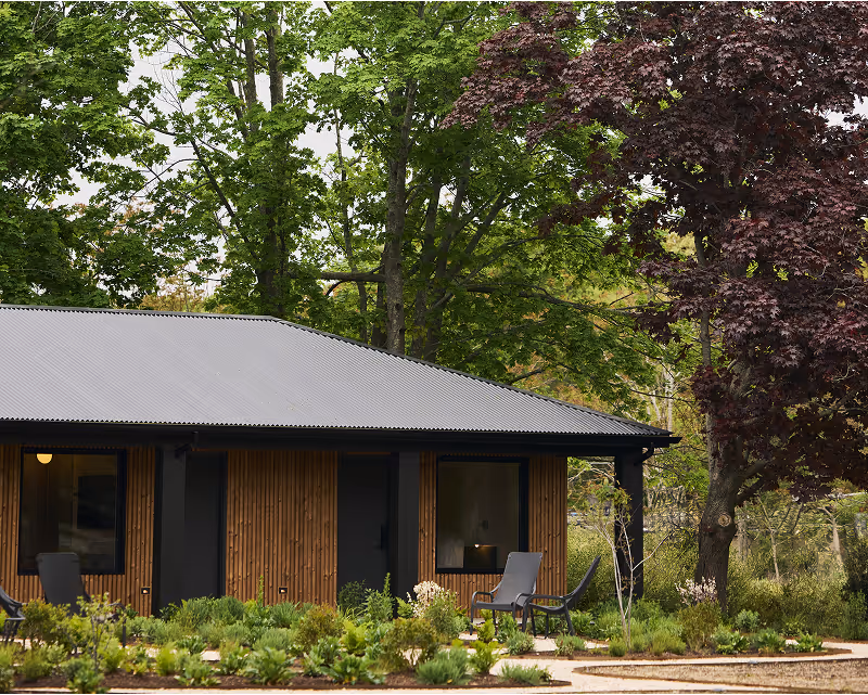 Wood paneled hotel building with black accents with trees behind
