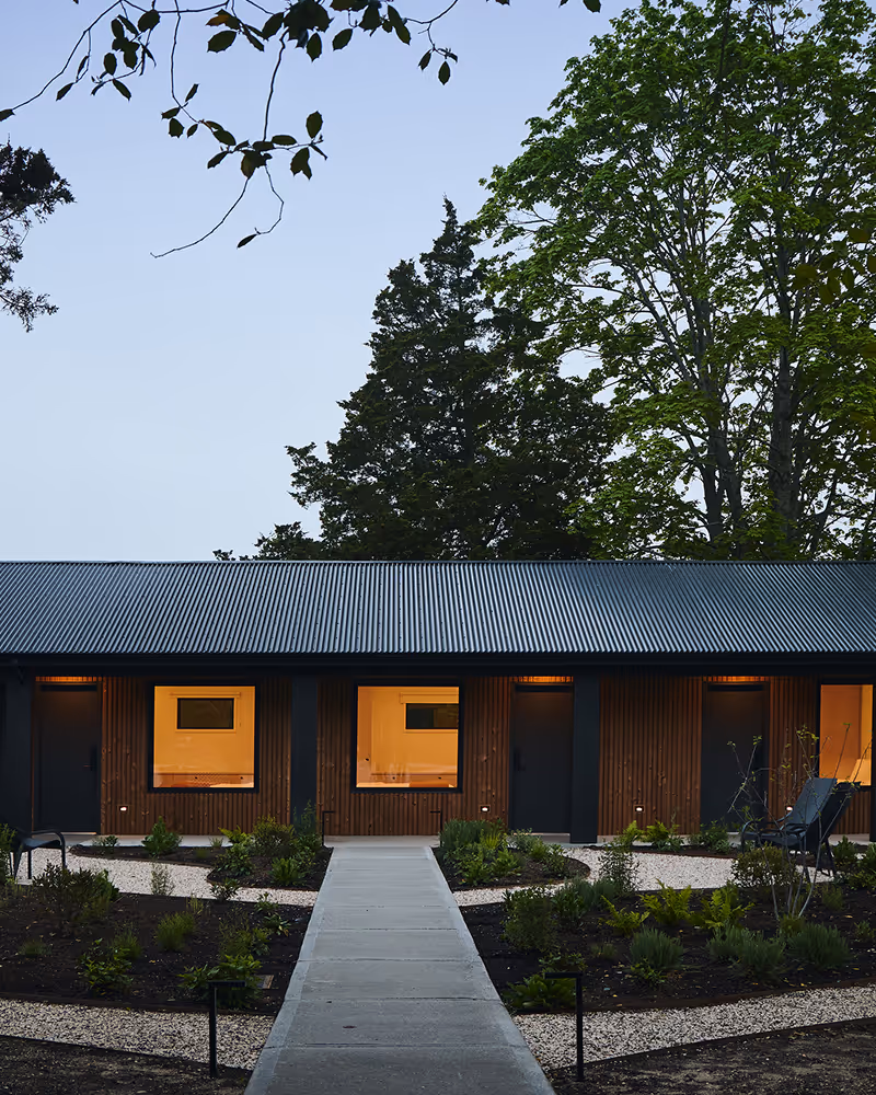 Evening view of main walkway that branches off into other walkways leading to wood paneled hotel building