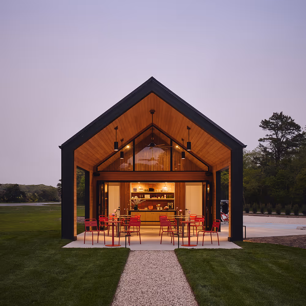 The Barn during sunset with the interior lit up and outdoor seating