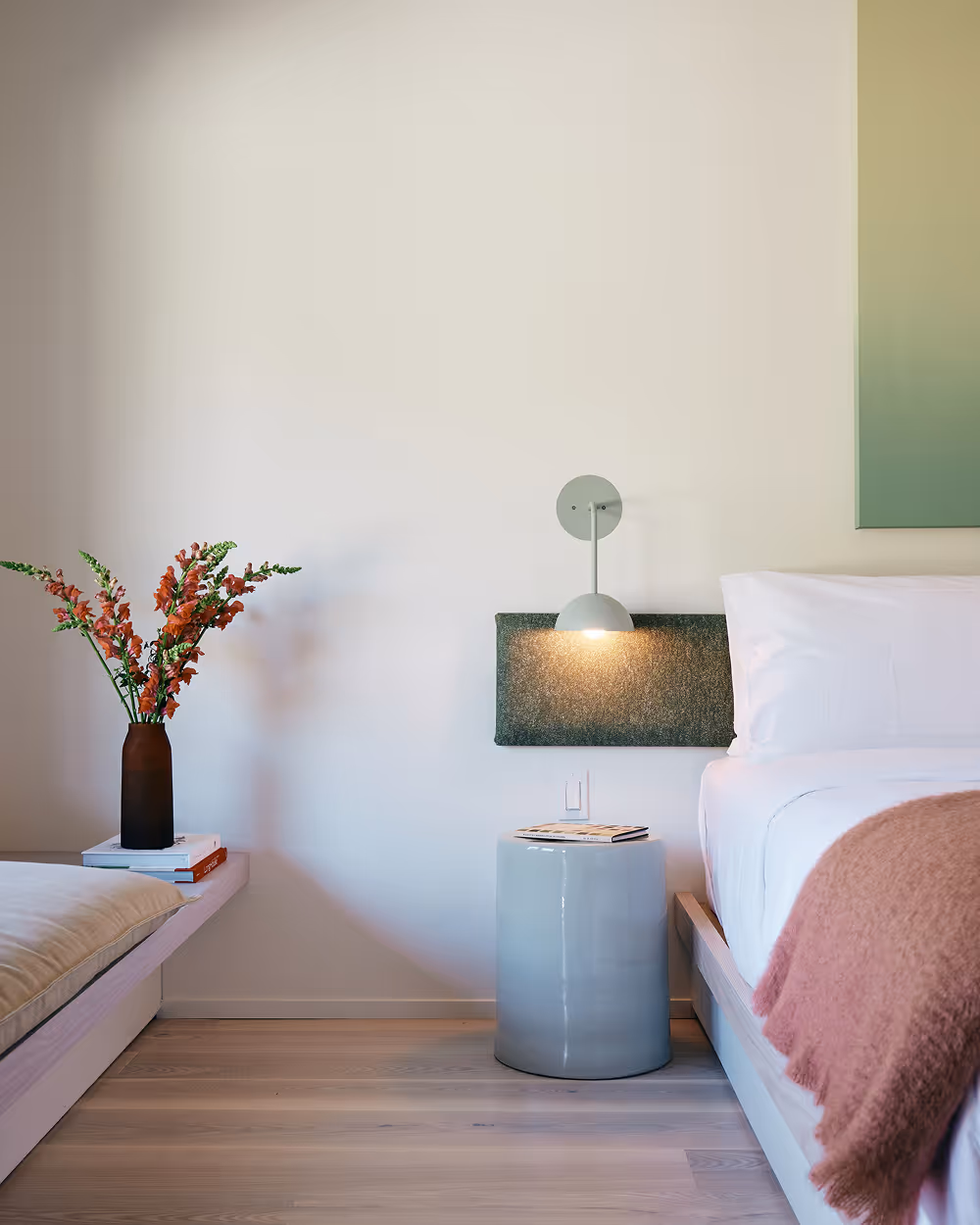 Close up view of king bed featuring a bouquet, side table, sconces, and the bed