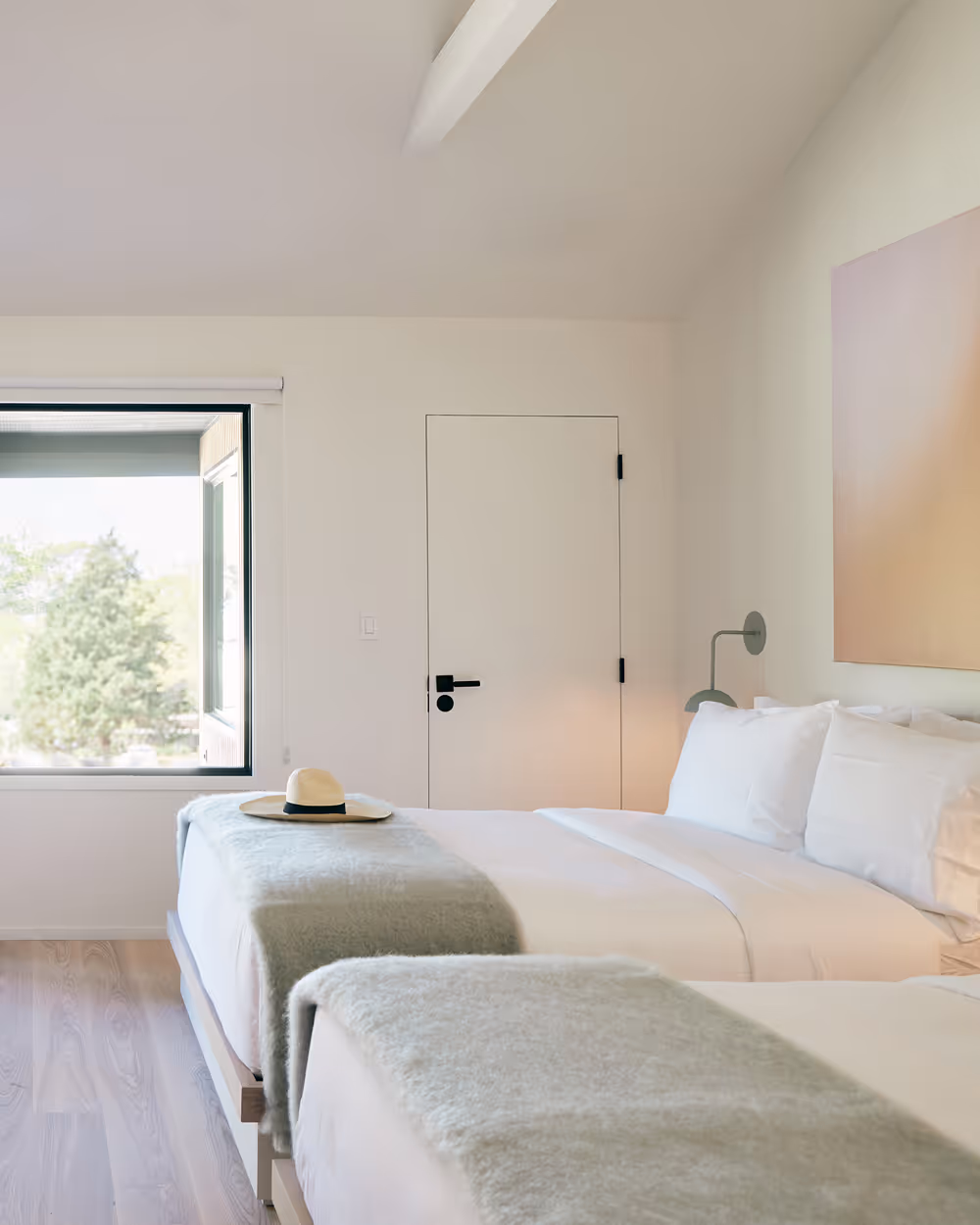 Side view of two queen beds looking towards a wall with a door leading to a private patio