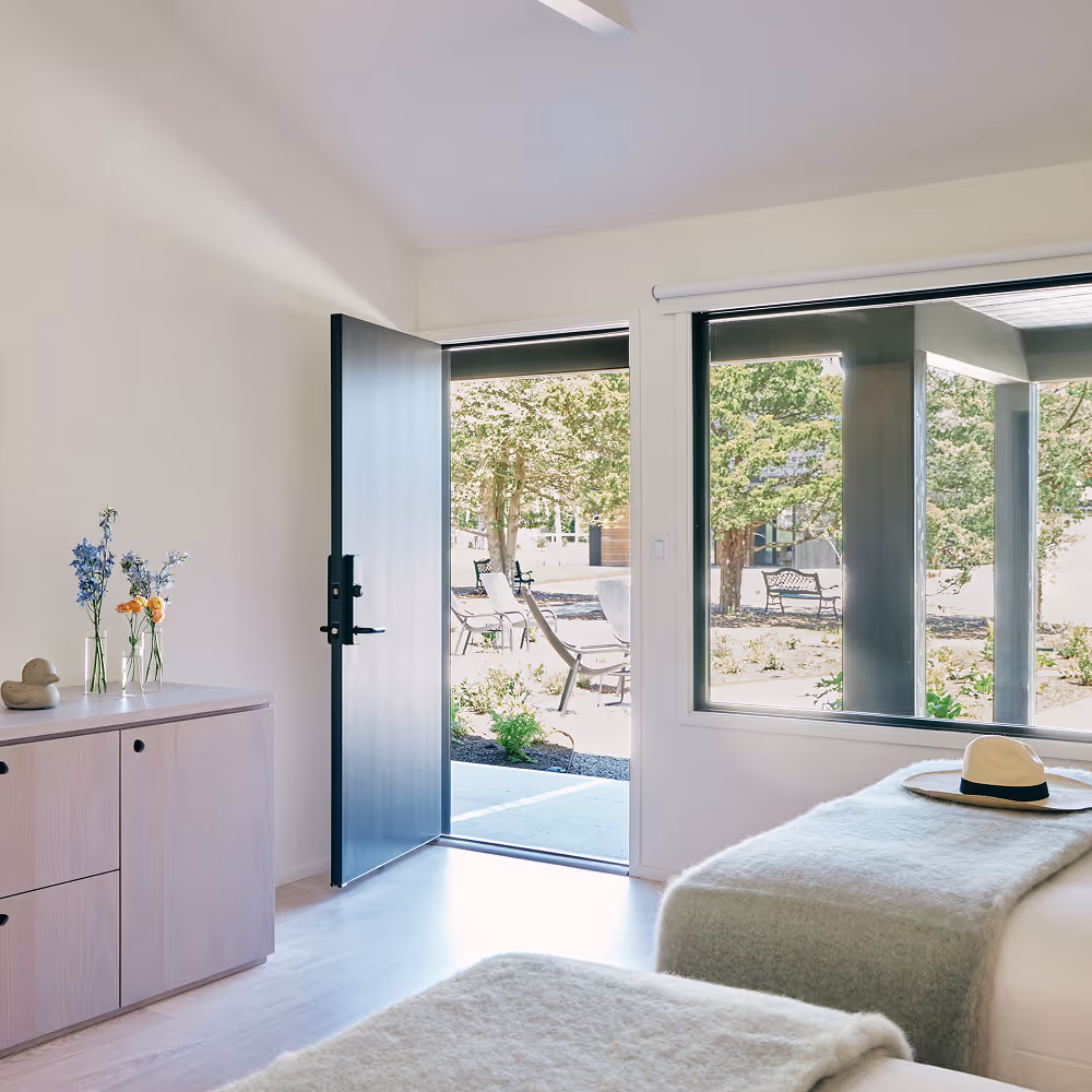 Angled view of two queen beds looking towards a wall with a door leading outdoors