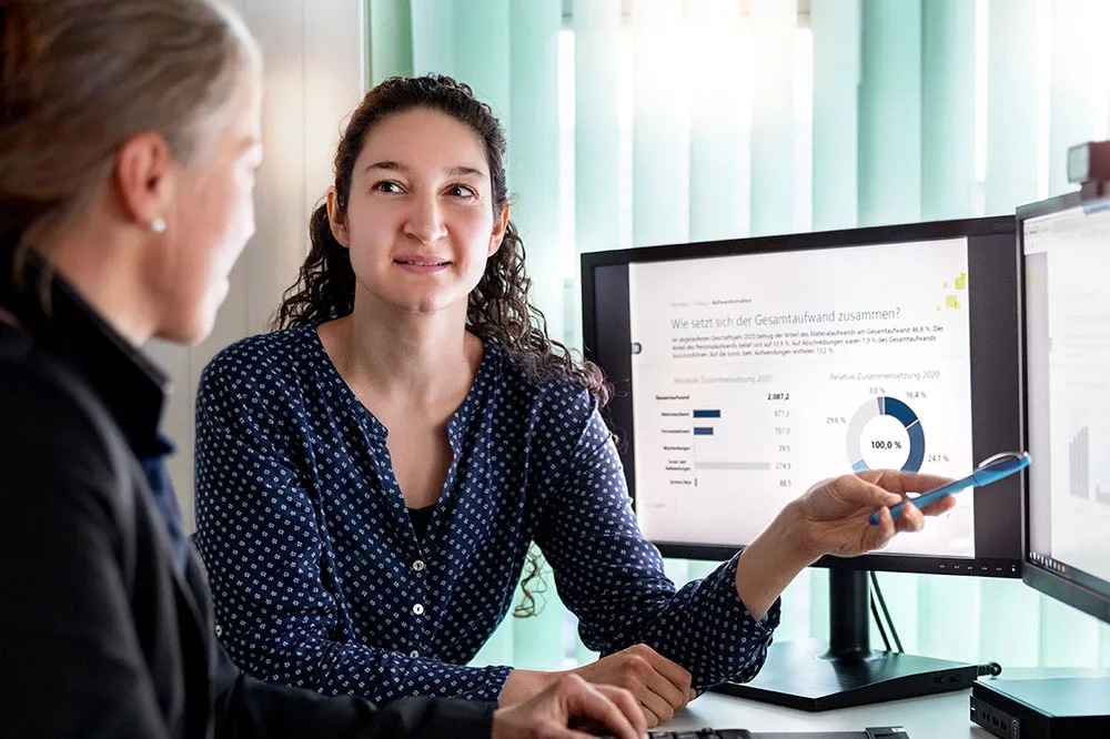 Zwei Frauen diskutieren vor einem Computerbildschirm mit einer geöffneten Präsentation