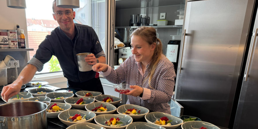 Sechs Geschäftsleute sitzen an einem runden Holztisch, trinken Kaffee und diskutieren Dokumente.