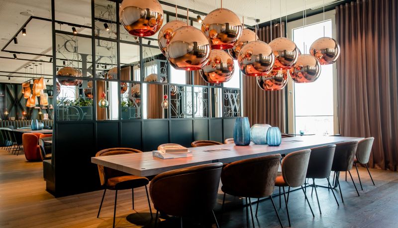 Sechs Geschäftsleute sitzen an einem runden Holztisch, trinken Kaffee und diskutieren Dokumente.