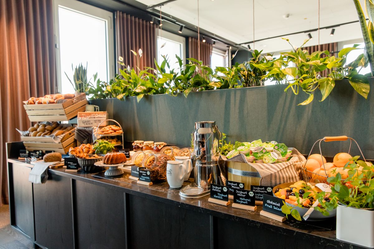 Sechs Geschäftsleute sitzen an einem runden Holztisch, trinken Kaffee und diskutieren Dokumente.
