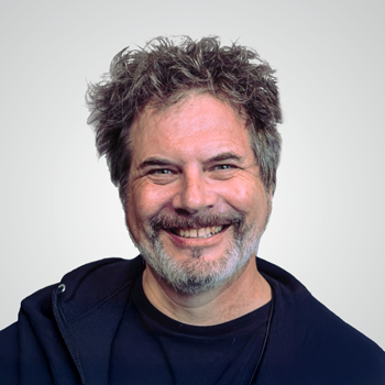 Portrait of Tod Beardsley wearing dark hoodie over dark t-shirt infront of pale gray backdrop