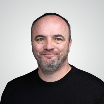 Portrait of Jerry Gablin wearing a dark t-shirt infront of pale gray backdrop
