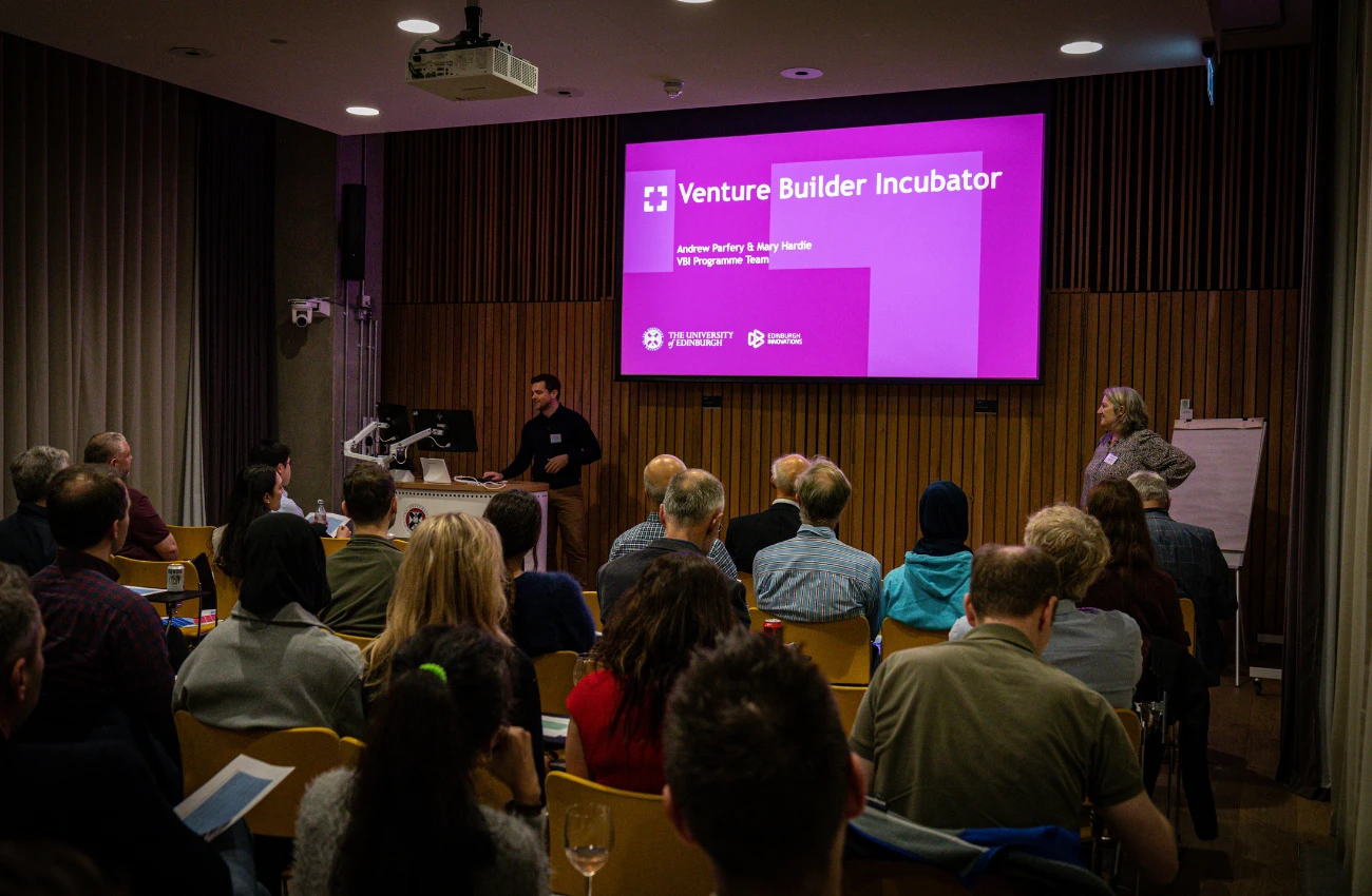 Audience attending a presentation in a conference room with a purple slide titled 'Venture Builder Incubator' from The University of Edinburgh and Edinburgh Innovations.