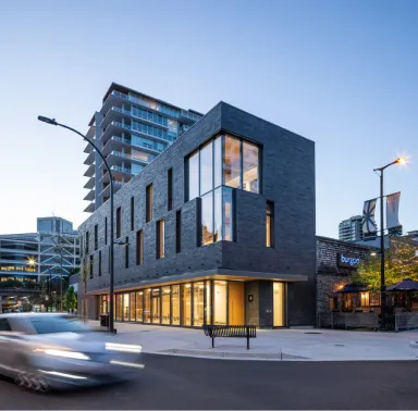 A car driving past a tall building on a city street.
