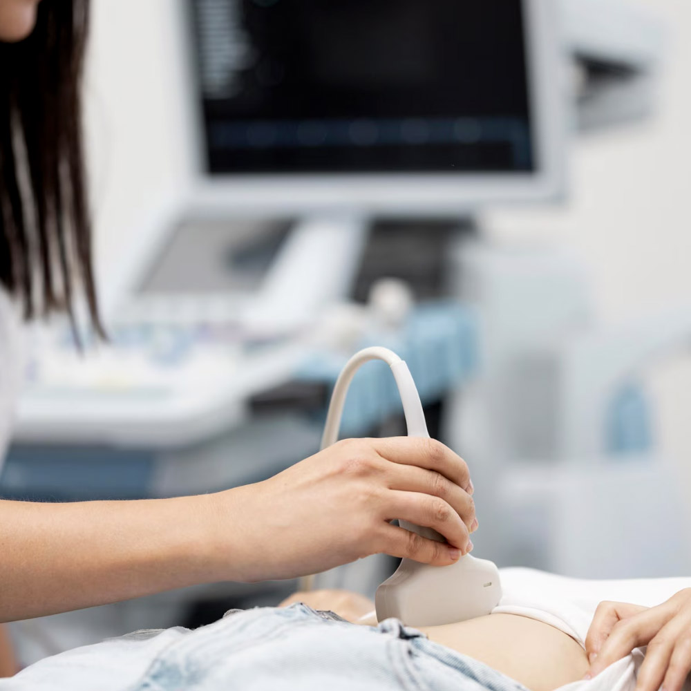 Healthcare professional performing an abdominal ultrasound scan on a patient in a clinical setting.
