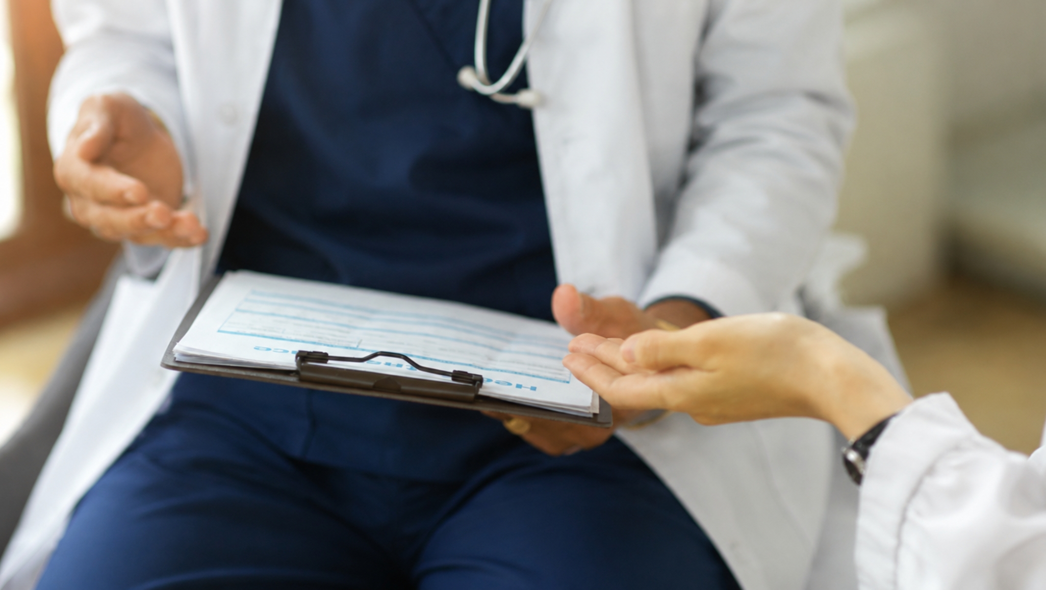 Healthcare professionals discussing patient information while reviewing medical documents during a clinical consultation.