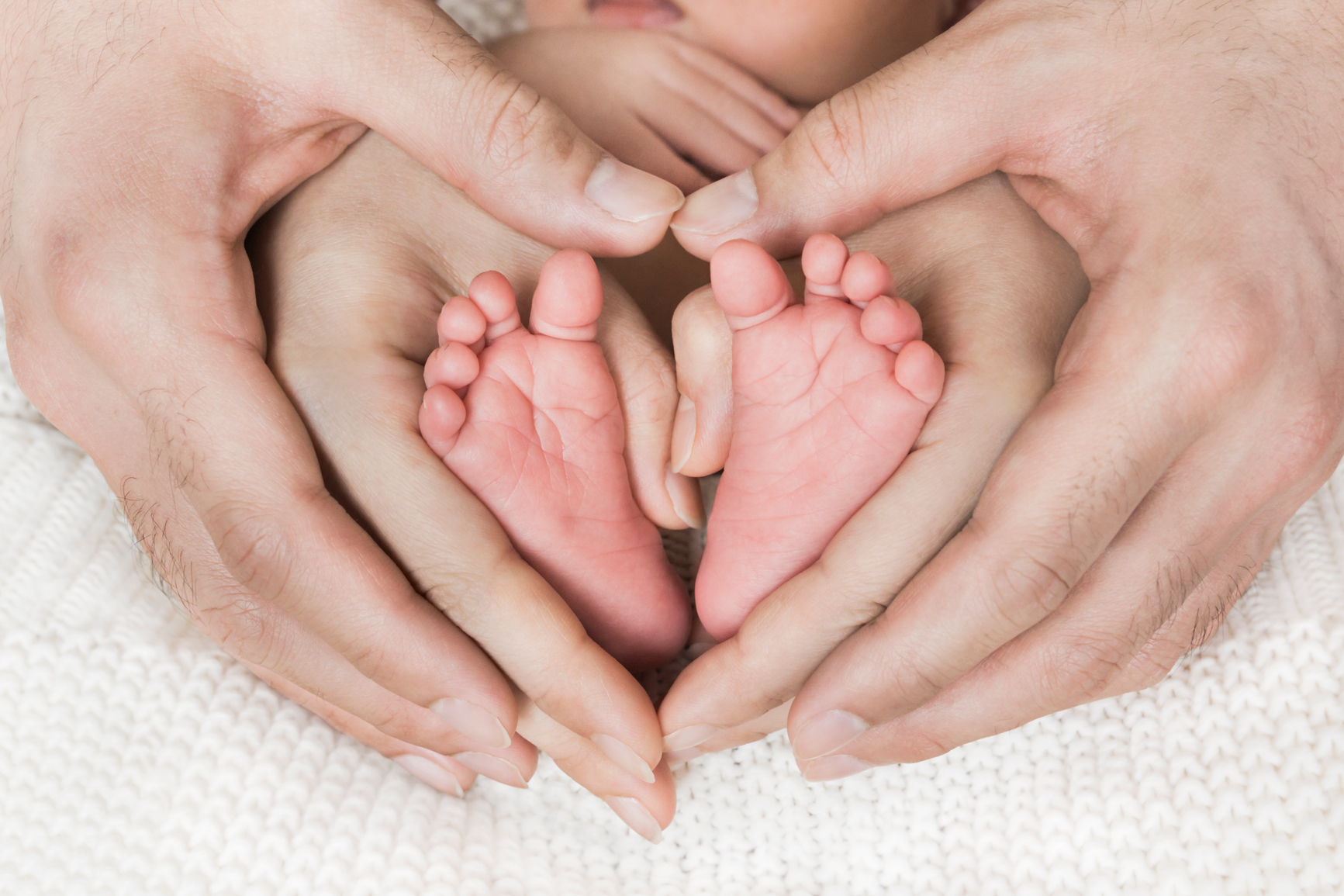 Hands form heart around baby's feet