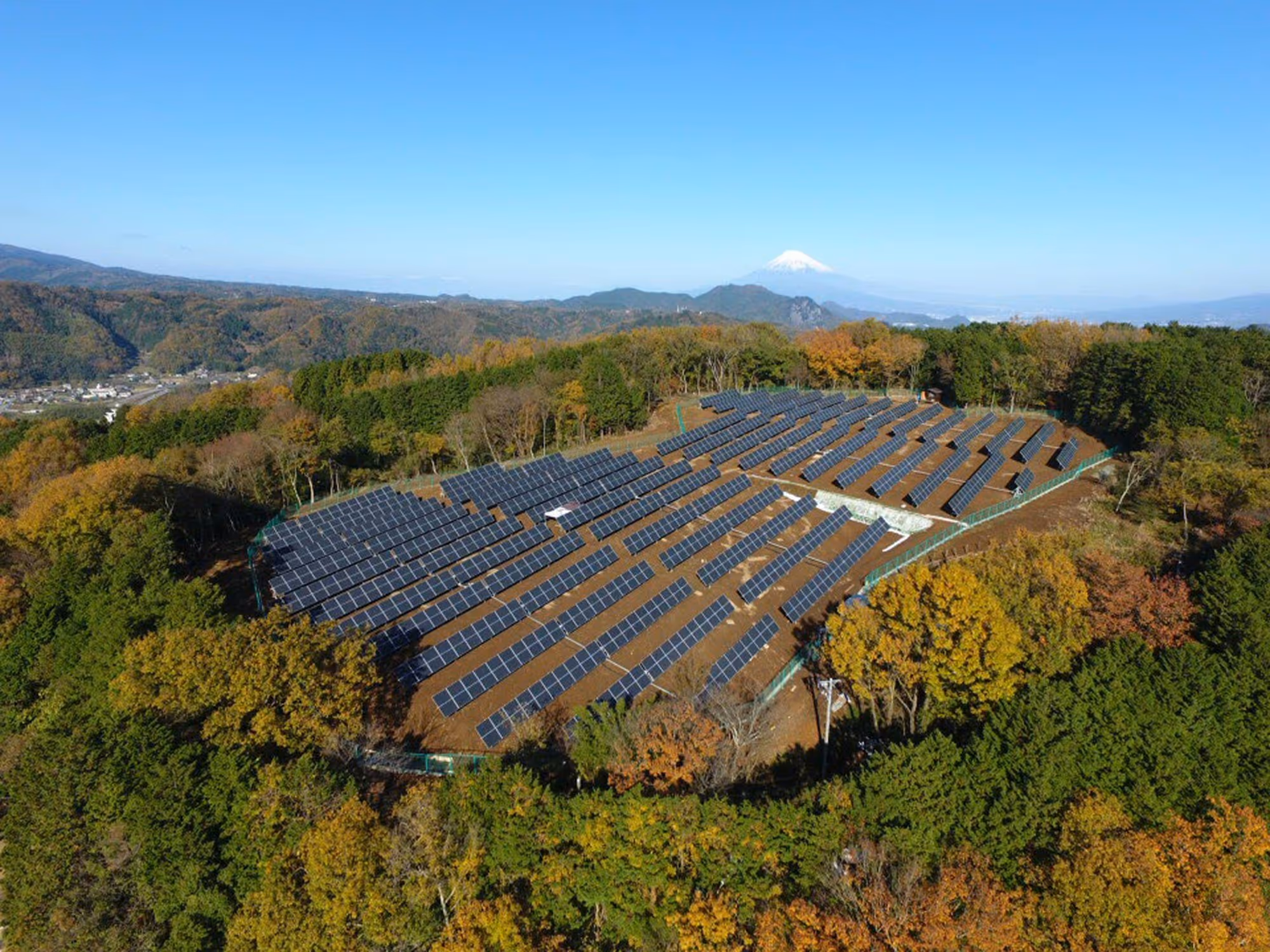 Solar farm surrounded by trees in the early stage of the leaves changing colors for autumn