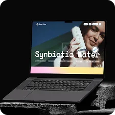 Laptop displaying a webpage with a woman holding a bottle and the text 'Synbiotic Water'.