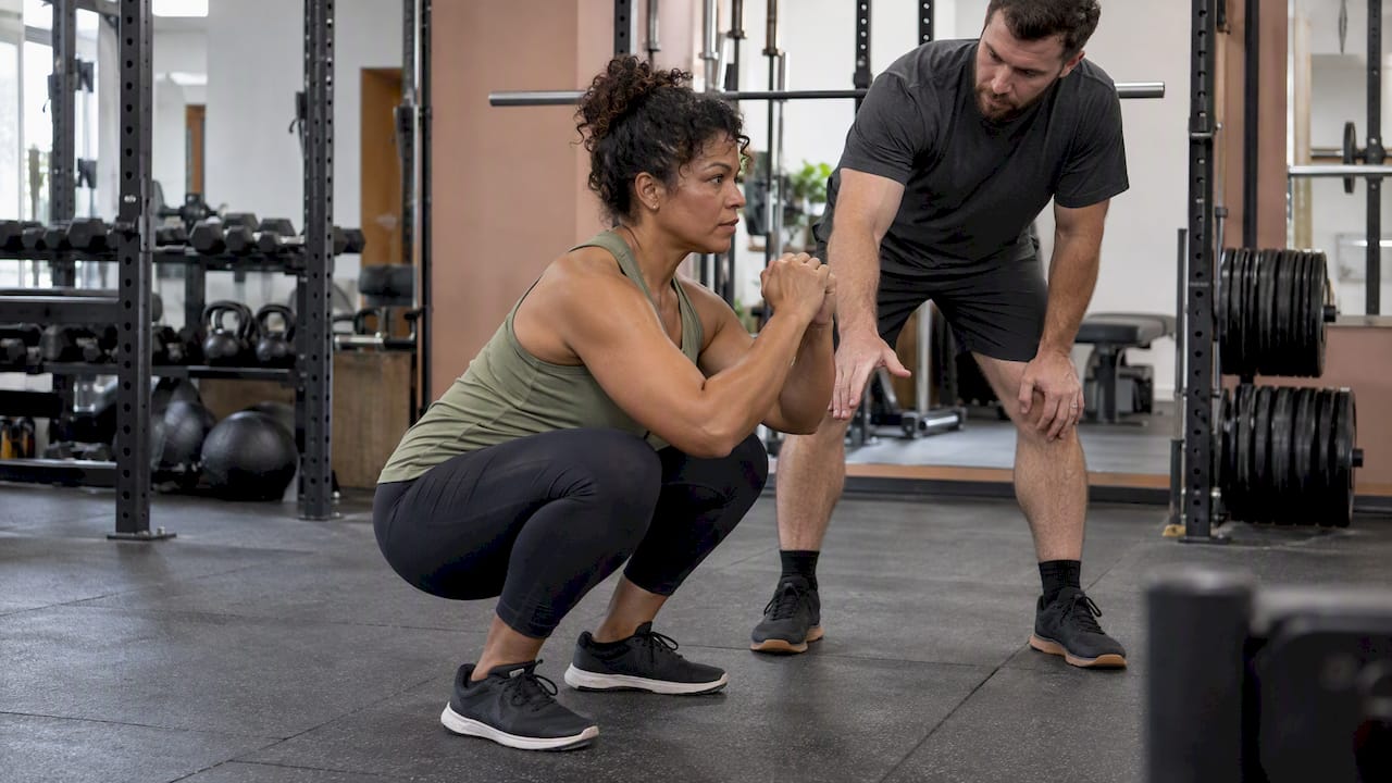 Coach guiding a controlled deep squat
