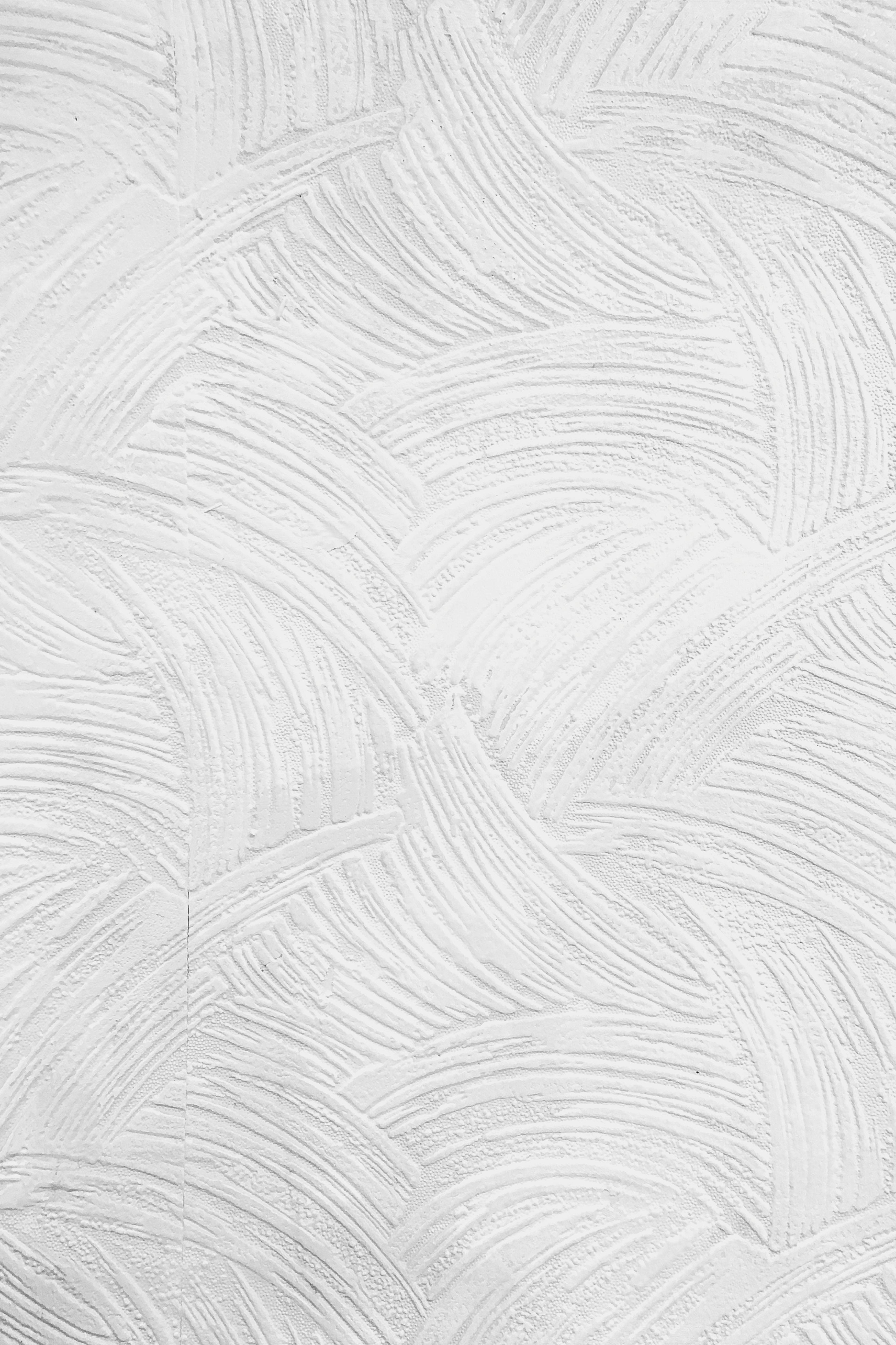 White textured wall with a repetitive, curved swirl pattern in plaster, reminiscent of the clean aesthetic often found in a dentist's office.